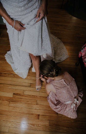 Junior bridesmaid helping bride with shoes