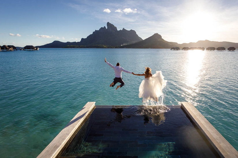 Bride and groom trashing the dress jumping from their bungalow at the Four Seasons Resort Bora Bora