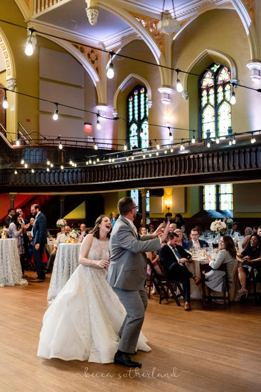 Bride and groom laugh while dancing