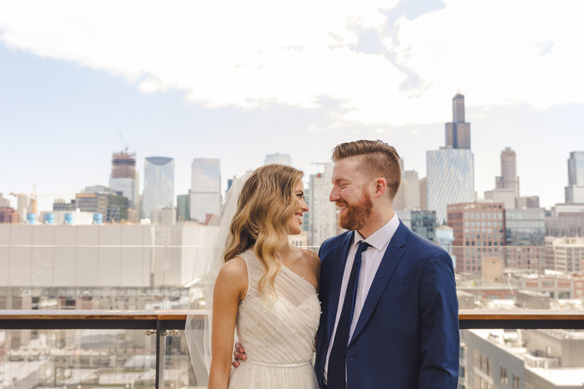 Bride and groom smile and look at each other with view of Chicago in the background